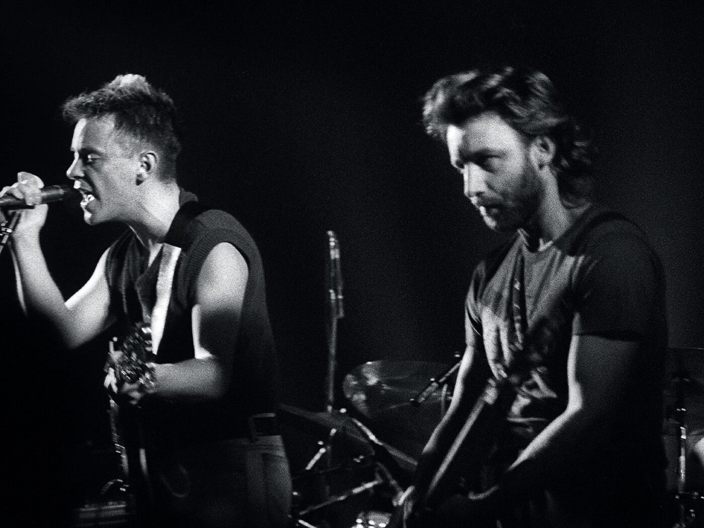 black and white photograph of New Order performing live in 1985