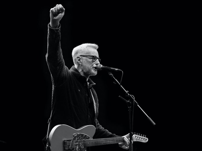 black and white photograph of Billy Bragg performing live onstage