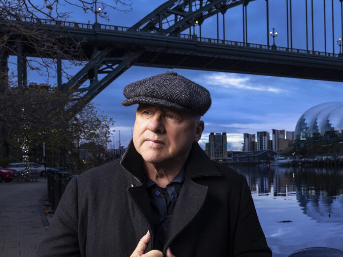 Mark Knopfler standing in front of the Tyne river bridge in new castle